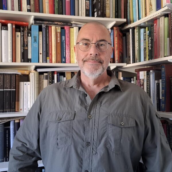 History, Heritage and Archaeology Lecturer Dr Sean McGlynn standing in a library.