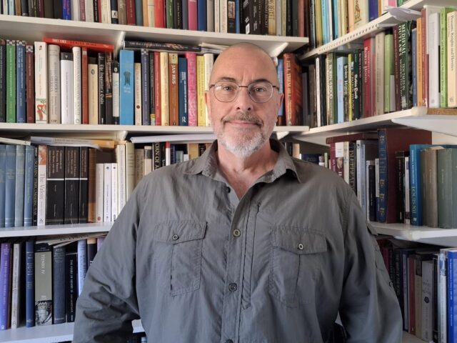 History, Heritage and Archaeology Lecturer Dr Sean McGlynn standing in a library.