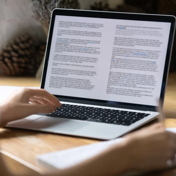 Person typing on a laptop with a document on the screen.