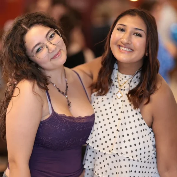 Two smiling women standing close together at a social event.