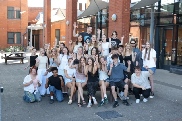 A group of young adults posing together outside a modern building.
