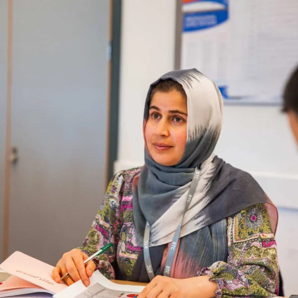 Two women sitting at a desk with papers and pens