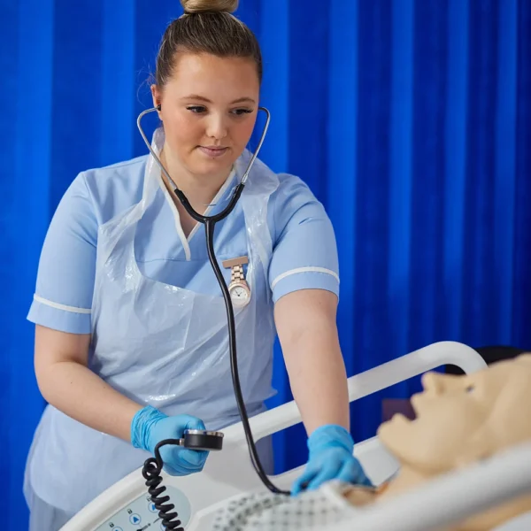 Nurse using a stethoscope on a mannequin in a hospital setting.