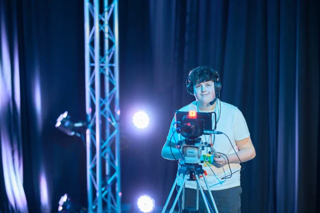 A man operating a video camera on a tripod.