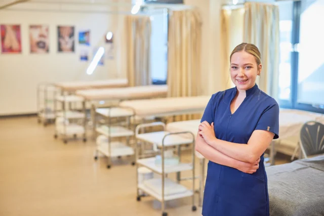 A healthcare professional standing in a hospital ward with medical equipment.