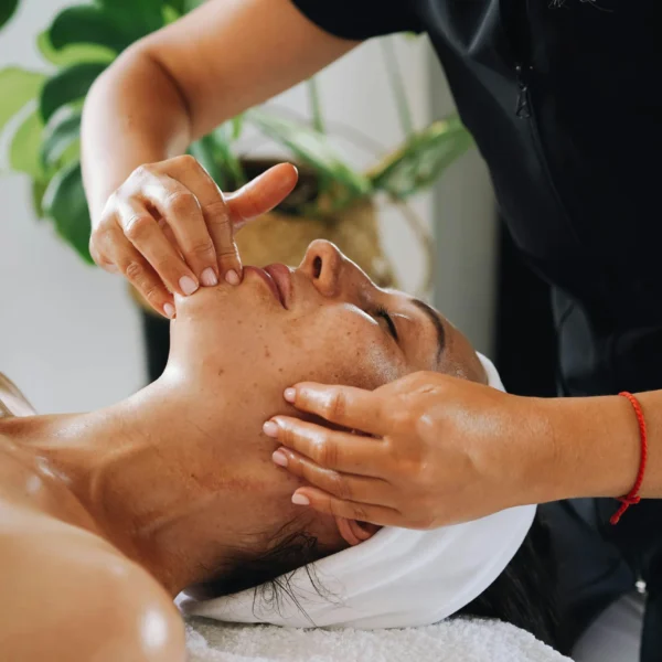 A woman receiving a facial massage from a therapist.