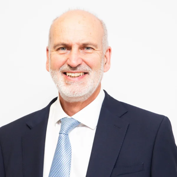 A smiling middle-aged man in a navy suit and light blue tie.