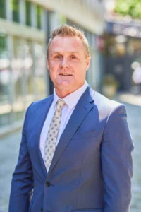 A man in a blue suit standing outside a modern building.
