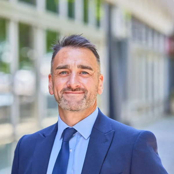 Professional man in a blue suit standing outside a modern building.