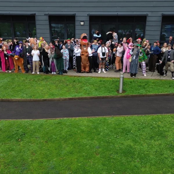 A group of people standing on grass outside a building