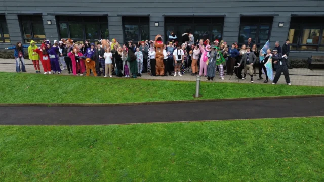 A group of people standing on grass outside a building