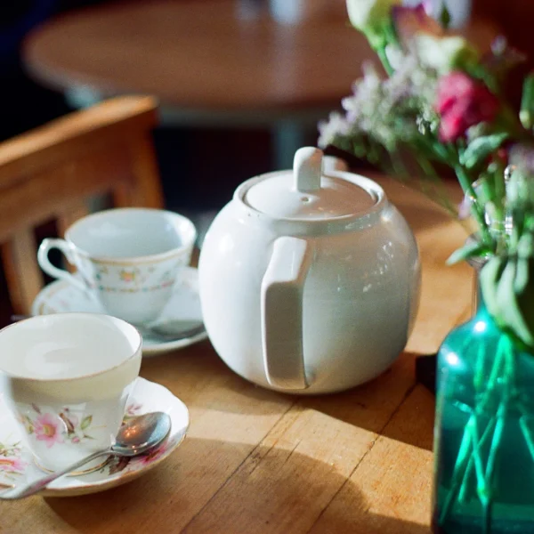A tea set on a table with a vase of flowers