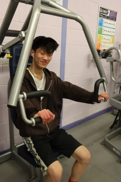 Young man working out on a machine at the gym, focused on his exercise.