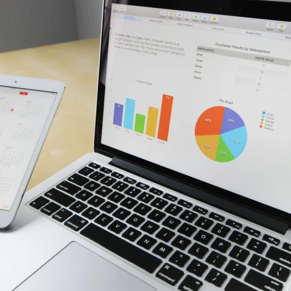 Laptop and tablet on a desk with graphs on the screens, showing data analysis and business statistics.