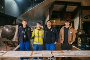 Four people standing in front of a large piece of machinery