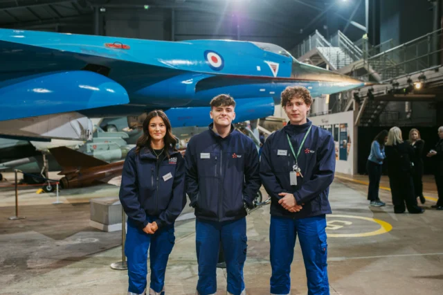 Three people standing in front of a blue airplane