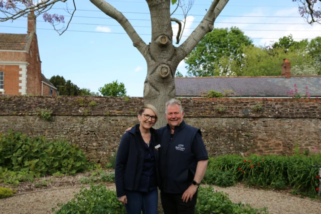 Couple standing in front of a tree with carvings on it.