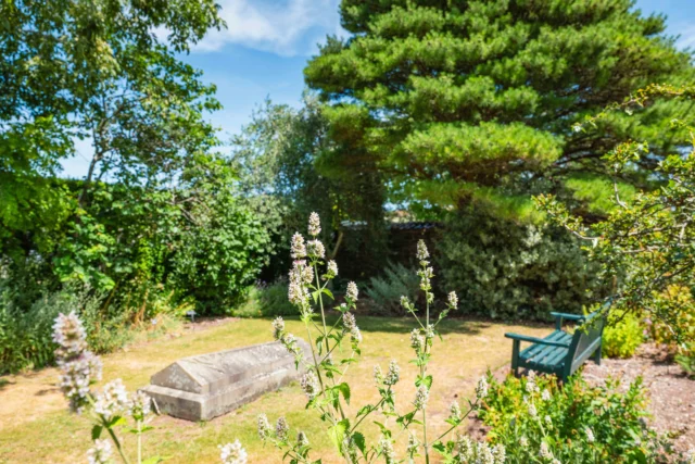 Image of a garden with a bench and a stone monument.