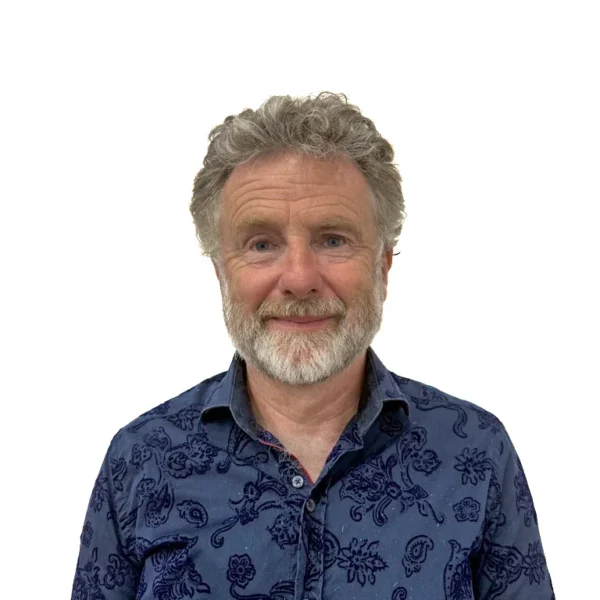 Middle-aged man with grey hair and beard wearing a blue patterned shirt.