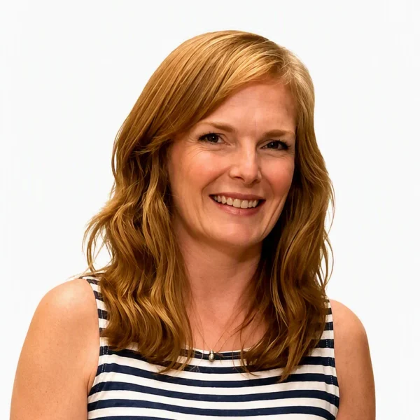 A woman with shoulder-length wavy hair smiling, wearing a navy and white striped sleeveless top against a plain white background.