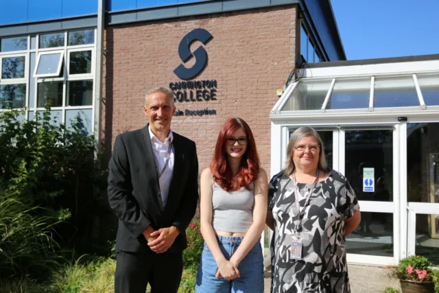 Three individuals standing outside Cavenham College, with the college's logo visible on the brick building behind them.