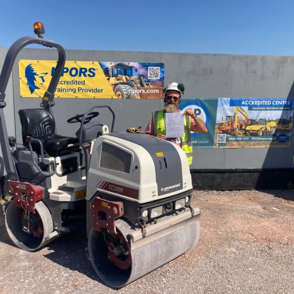 A construction worker stands beside a road roller in front of a wall with ACCORD branding.