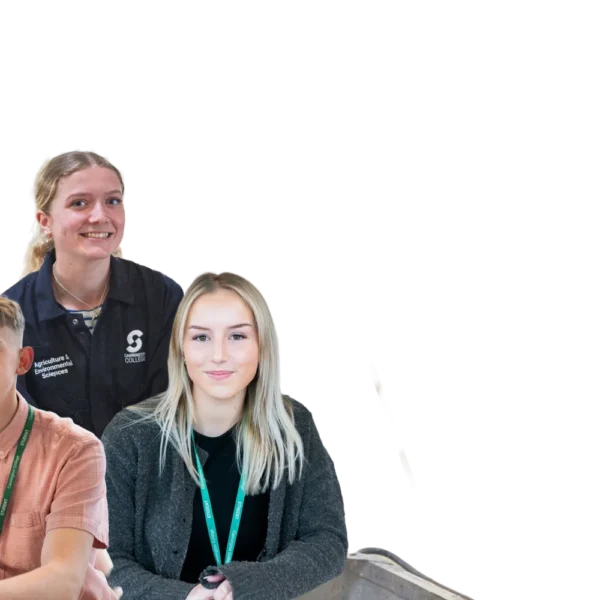 Three individuals posing together, two seated and one standing, all wearing lanyards, likely at an event or workshop.