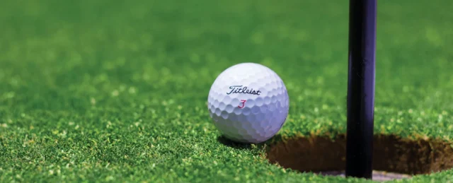 a white golf ball on a green course near a hole