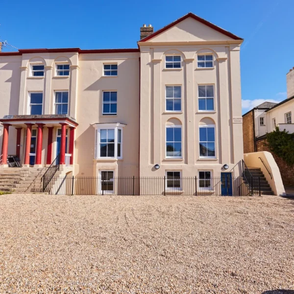 Large beige building with red trim and gravel driveway