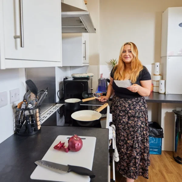 Woman standing by a kitchen counter with cooking items.