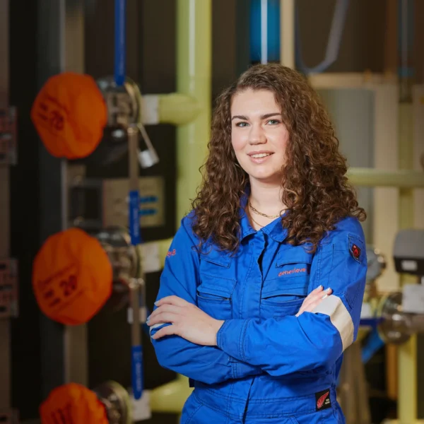 A female Nuclear Engineering Degree Apprentice in blue uniform standing in industrial setting