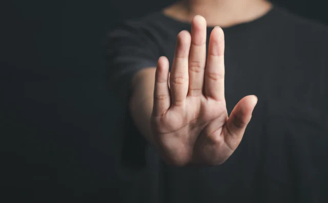 A person's hand raised in a stopping or rejecting motion