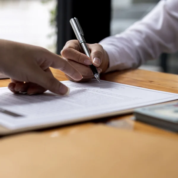 A person signing a document on a clipboard