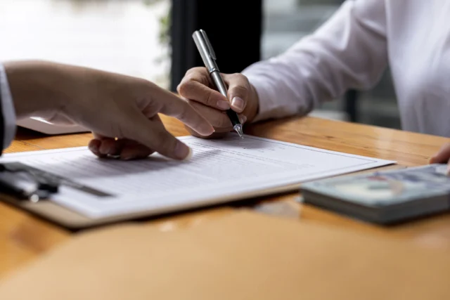 A person signing a document on a clipboard