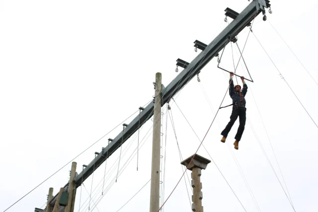 Person navigating a challenging rope course with focus and determination.