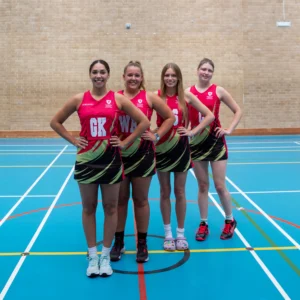 Four female UCS netball players in matching uniforms posing on a court