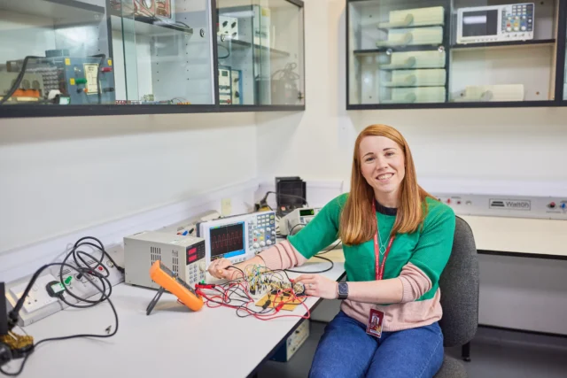 Woman working with electronic equipment in a lab.