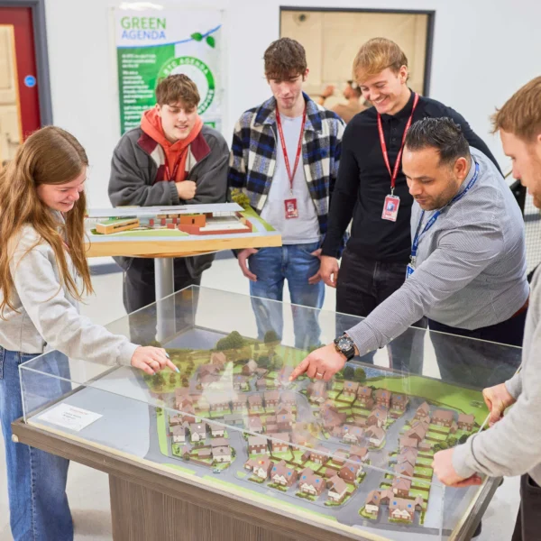 Group of students gathered around an interactive table model, exploring urban planning.