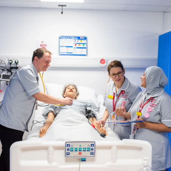 Medical team attending to a patient in a hospital bed.