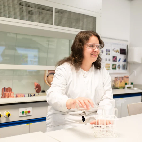 A woman in a lab setting measuring a liquid.