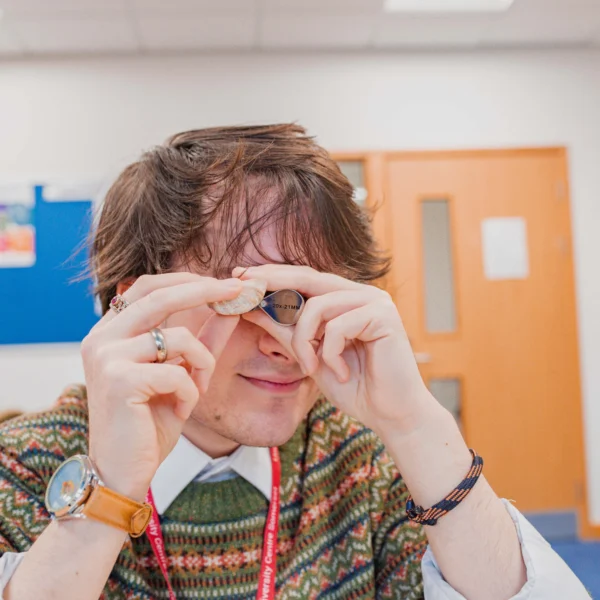 A person with short hair taking a close look at an object