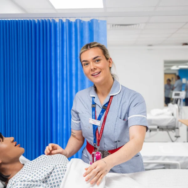 Nurse smiling and helping a patient in a hospital bed