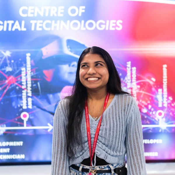 A young woman standing in front of a screen displaying 'Centre of Digital Technologies'.