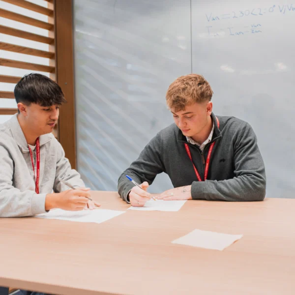 Two men sitting at a table with papers in front of them.