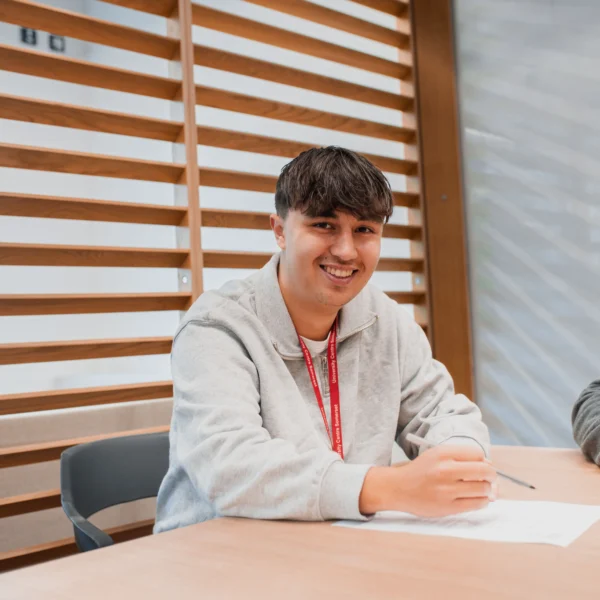 Young man sitting at a table with a smile on his face
