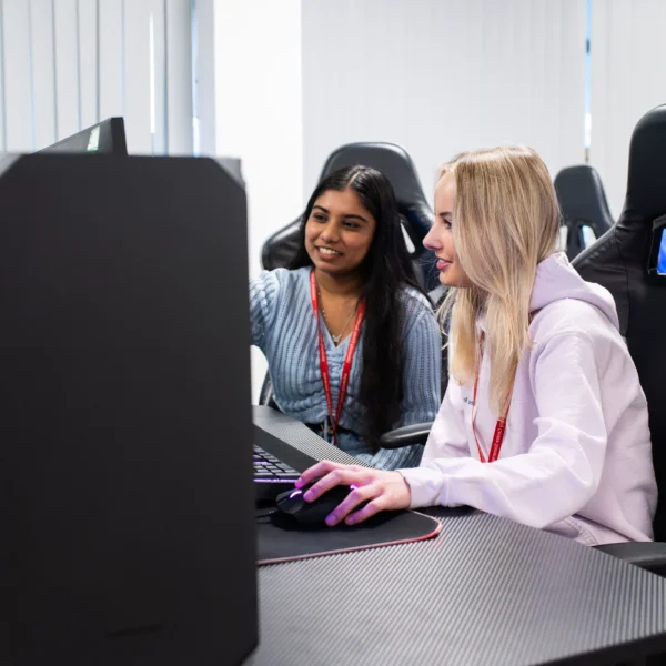 Two young women working together on a computer.