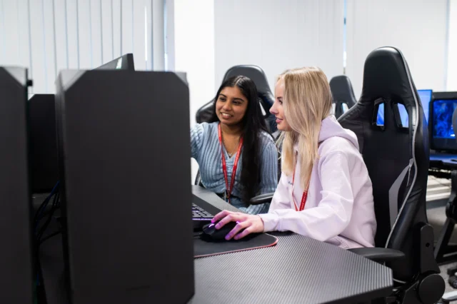Two young women working together on a computer.