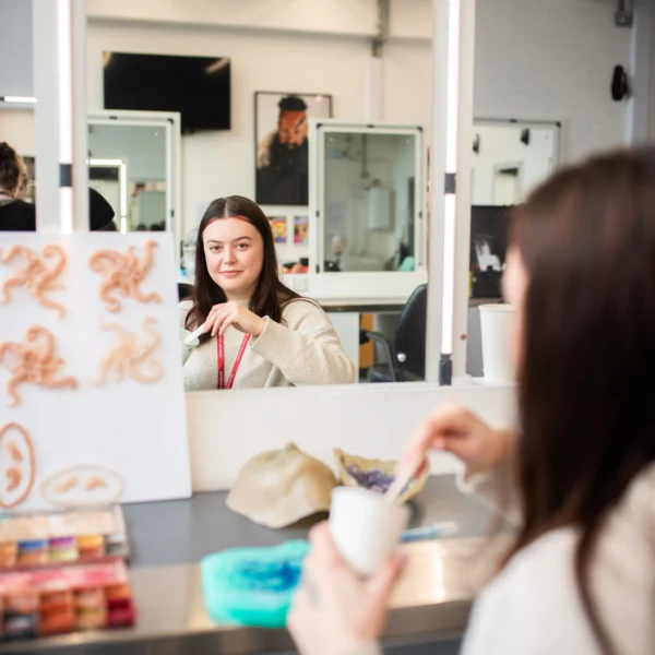 a woman applying makeup in front of a mirror