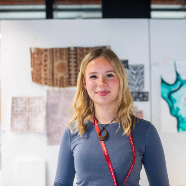 A young woman smiling in an art studio.