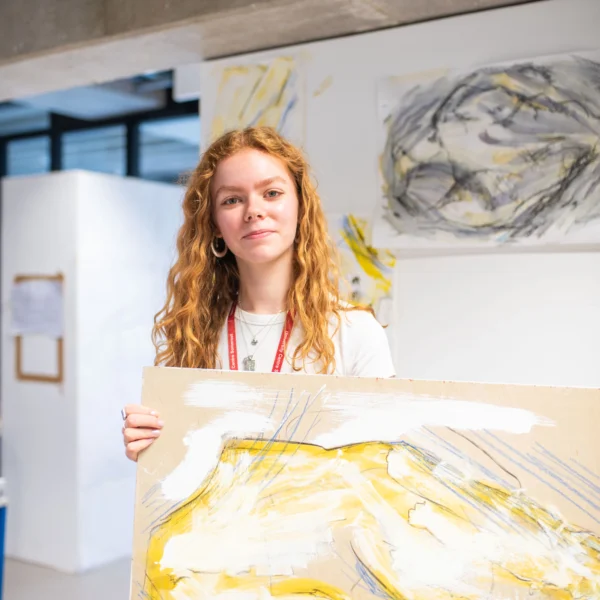 a woman holding a large piece of abstract art